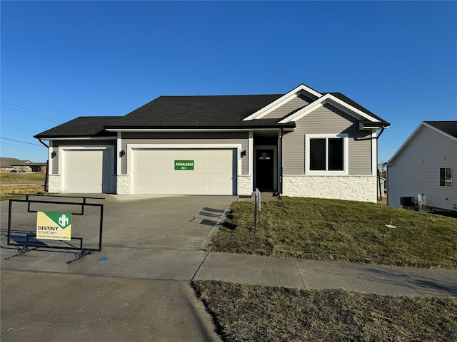 view of front of property with a garage, a front lawn, and central air condition unit