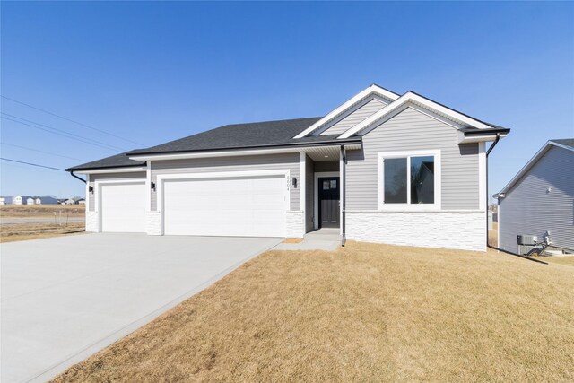 ranch-style home featuring driveway, stone siding, a front lawn, and an attached garage