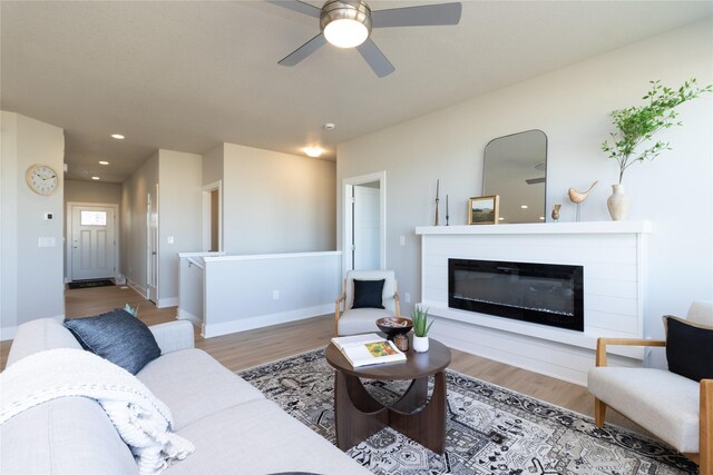 living room with recessed lighting, a glass covered fireplace, ceiling fan, wood finished floors, and baseboards