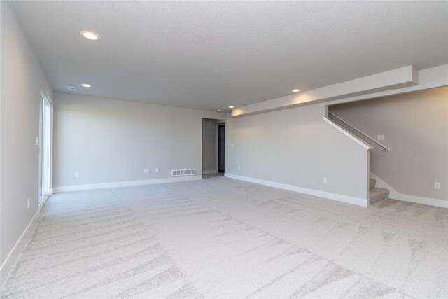 empty room with light carpet, baseboards, visible vents, stairway, and recessed lighting