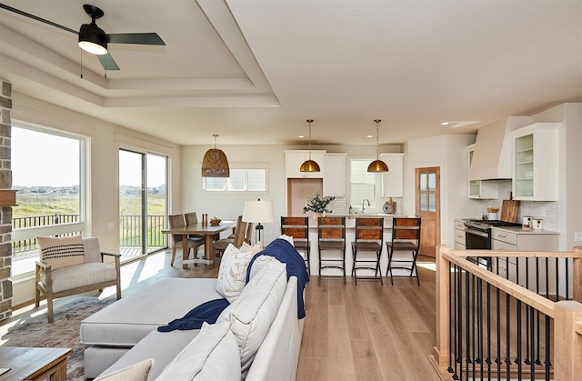 living room featuring ceiling fan, sink, light hardwood / wood-style floors, and a wealth of natural light