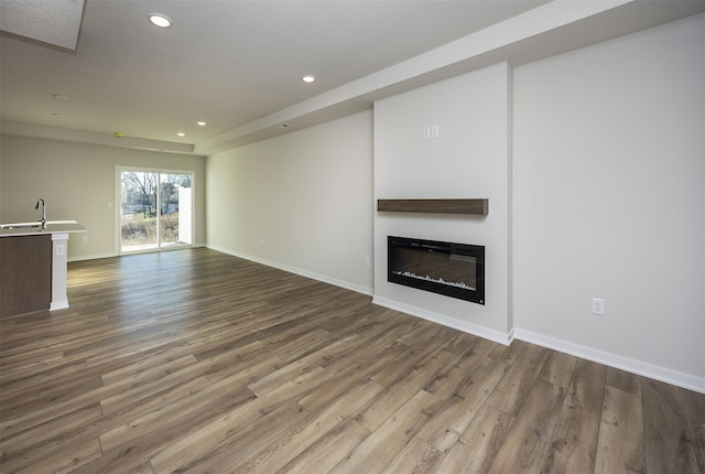 unfurnished living room featuring hardwood / wood-style floors and sink