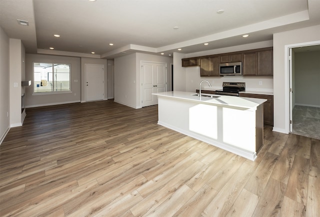 kitchen with a center island with sink, light hardwood / wood-style floors, sink, and appliances with stainless steel finishes