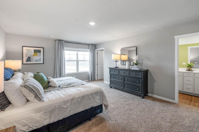 bedroom with light carpet, a textured ceiling, ensuite bath, and baseboards
