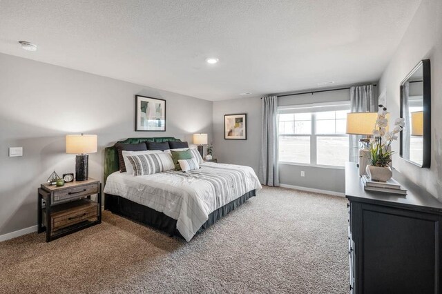 bedroom with light colored carpet, baseboards, and a textured ceiling
