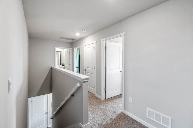 hall featuring carpet, visible vents, baseboards, recessed lighting, and an upstairs landing