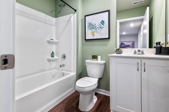 bathroom with visible vents, toilet, shower / bathing tub combination, wood finished floors, and vanity