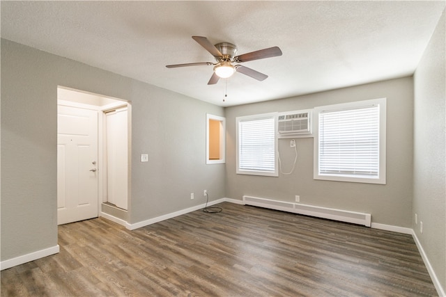 unfurnished room with wood-type flooring, a wall unit AC, a baseboard radiator, and ceiling fan