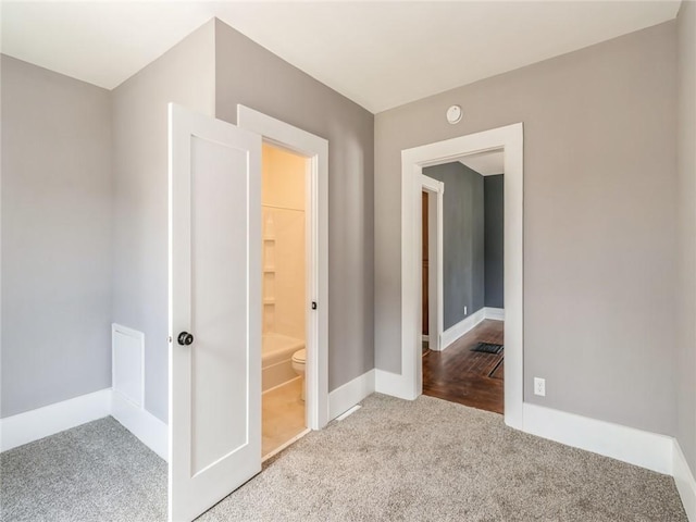 interior space with ensuite bathroom and light carpet