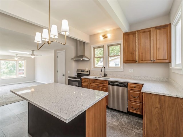 kitchen with pendant lighting, ceiling fan with notable chandelier, sink, wall chimney exhaust hood, and stainless steel appliances