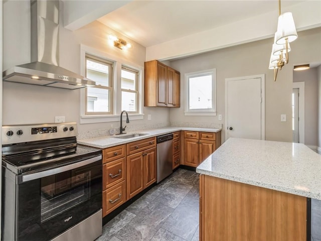 kitchen with wall chimney range hood, sink, hanging light fixtures, light stone counters, and stainless steel appliances