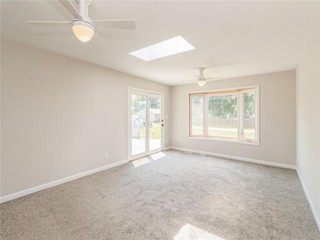 unfurnished room featuring carpet flooring, ceiling fan, and a skylight