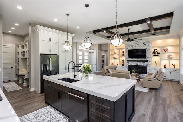 kitchen featuring stainless steel appliances, sink, decorative light fixtures, white cabinets, and a stone fireplace