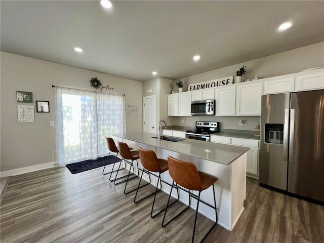 kitchen featuring sink, appliances with stainless steel finishes, a kitchen island with sink, white cabinetry, and a kitchen breakfast bar