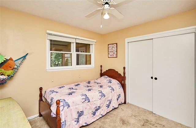 bedroom with a textured ceiling, light colored carpet, ceiling fan, and a closet