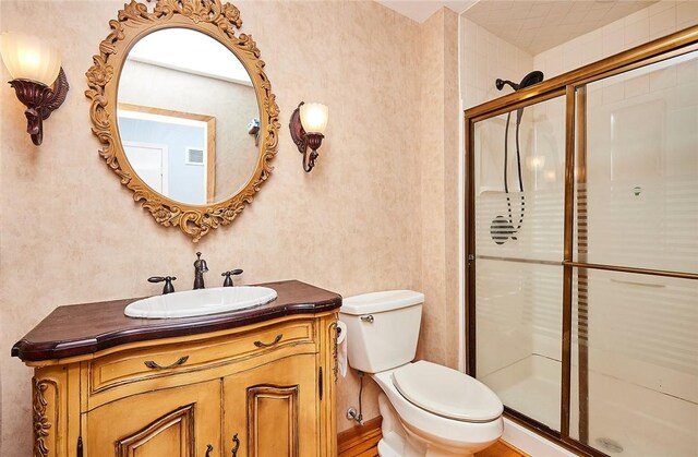 bathroom with toilet, a shower with door, and vanity