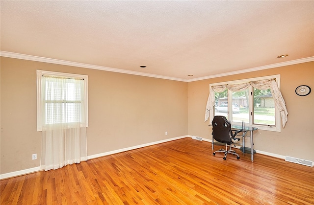 unfurnished office featuring crown molding, plenty of natural light, and hardwood / wood-style floors