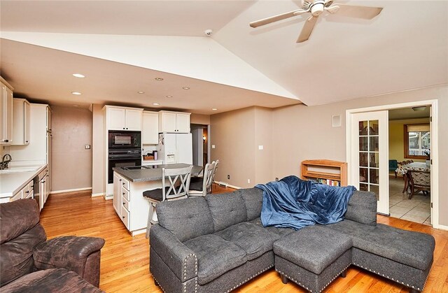 living room with lofted ceiling, sink, ceiling fan, and light hardwood / wood-style floors