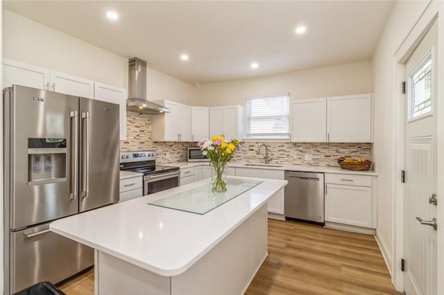 kitchen with wall chimney exhaust hood, stainless steel appliances, a center island, and white cabinets