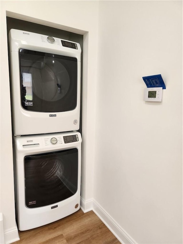 laundry area featuring stacked washer and clothes dryer and hardwood / wood-style floors