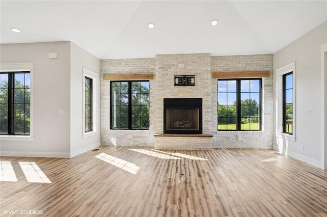 unfurnished living room featuring a wealth of natural light, a brick fireplace, and lofted ceiling