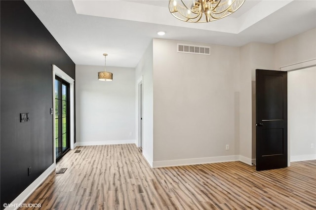 spare room featuring an inviting chandelier and hardwood / wood-style floors