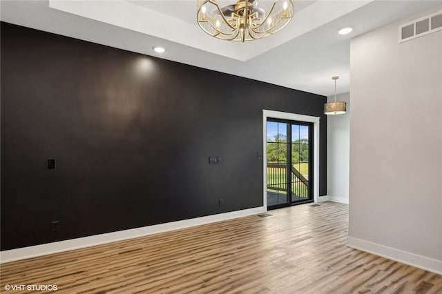 empty room featuring hardwood / wood-style flooring and an inviting chandelier