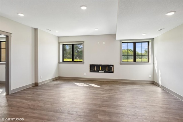 unfurnished living room featuring a healthy amount of sunlight, wood-type flooring, and a fireplace