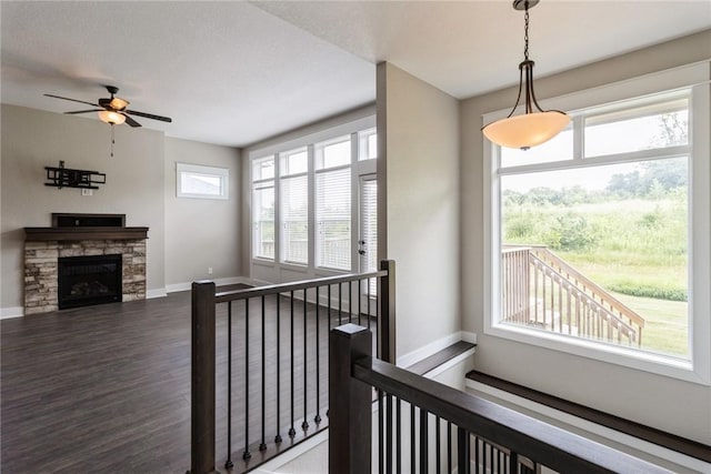 stairway with hardwood / wood-style flooring, ceiling fan, and a fireplace