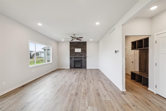 unfurnished living room featuring a large fireplace, ceiling fan, and light hardwood / wood-style flooring