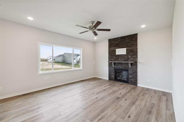 unfurnished living room with ceiling fan, a fireplace, and light wood-type flooring