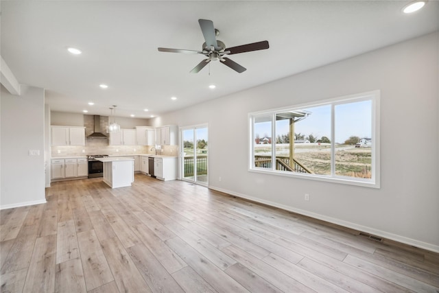 unfurnished living room featuring sink, light hardwood / wood-style floors, and ceiling fan