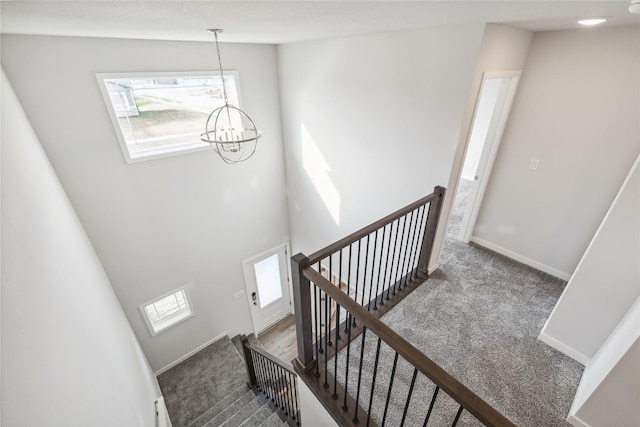 stairs featuring an inviting chandelier, a towering ceiling, and carpet