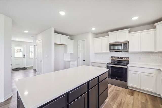 kitchen with a center island, appliances with stainless steel finishes, light wood-type flooring, and white cabinetry