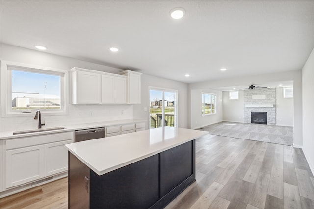 kitchen featuring a kitchen island, sink, white cabinets, a fireplace, and light hardwood / wood-style floors