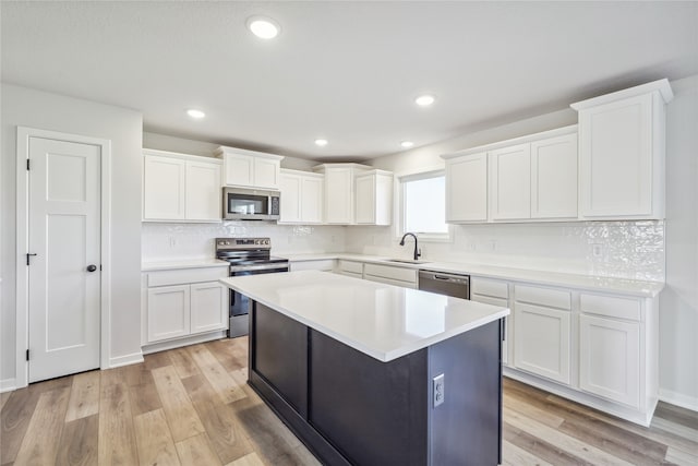 kitchen with stainless steel appliances, light wood-type flooring, and white cabinets