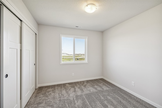 unfurnished bedroom with a closet, a textured ceiling, and carpet floors