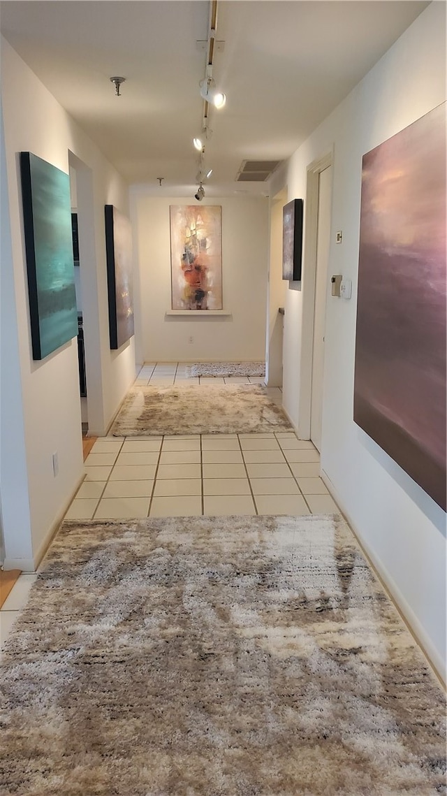 corridor featuring track lighting and light tile patterned floors