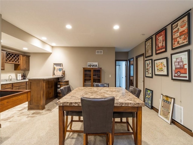 dining space featuring light colored carpet and wet bar