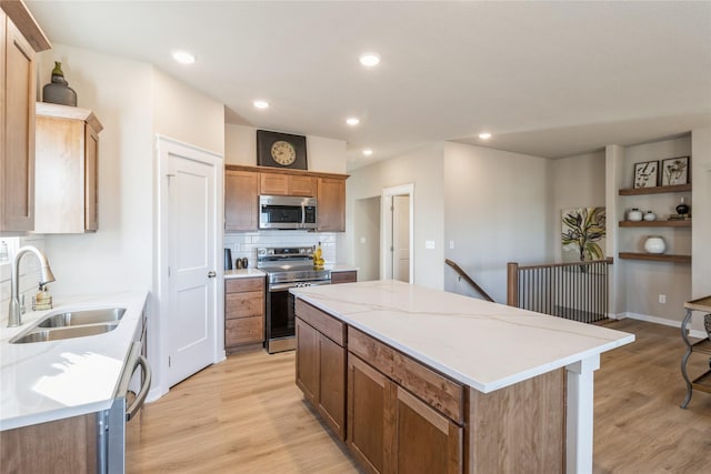 kitchen with sink, light wood-type flooring, stainless steel appliances, and a kitchen island