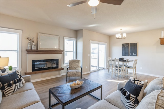 living room featuring ceiling fan with notable chandelier and light hardwood / wood-style floors