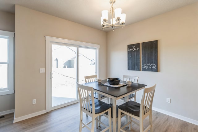 dining space with light hardwood / wood-style floors and a notable chandelier