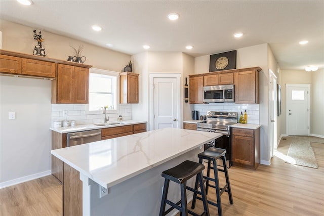 kitchen featuring a kitchen bar, sink, light hardwood / wood-style flooring, appliances with stainless steel finishes, and a kitchen island