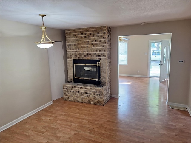 unfurnished living room with a fireplace, a textured ceiling, and hardwood / wood-style flooring