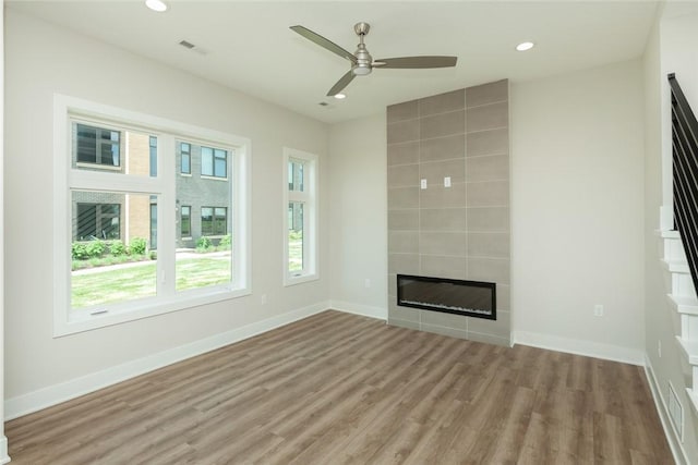 unfurnished living room with a tile fireplace, light hardwood / wood-style flooring, and ceiling fan