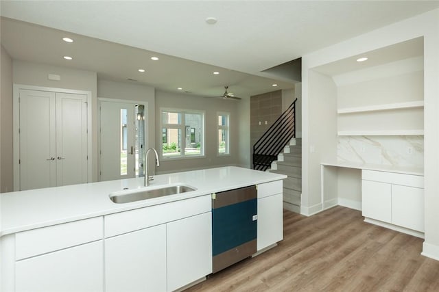 kitchen featuring backsplash, dishwasher, sink, and white cabinetry