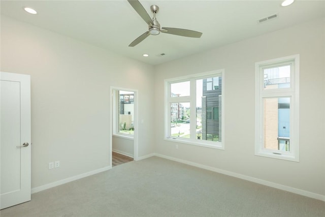 empty room featuring ceiling fan, light carpet, and a wealth of natural light