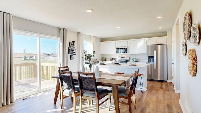 dining space featuring recessed lighting, baseboards, and light wood finished floors