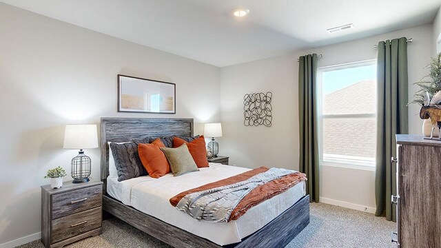 bedroom featuring visible vents, light colored carpet, and baseboards