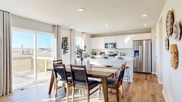 dining area with recessed lighting, light wood-type flooring, and baseboards